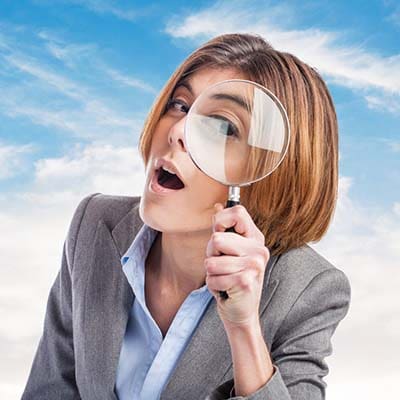 A business woman utilizing a magnifying glass to examine components of digital marketing.
